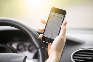 Close-up of traveler female hand holding her phone with navigation, driving while using cell phone for navigating, setting a destination