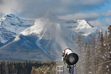 Snow gun for ski hill mountain in background