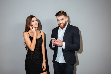 Two young businesspeople in smart wear holding mobile phones