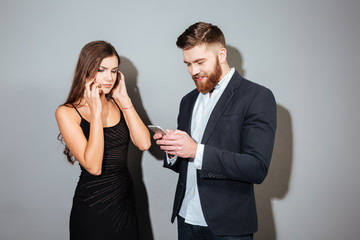 Two young businesspeople in smart clothes using mobile phones