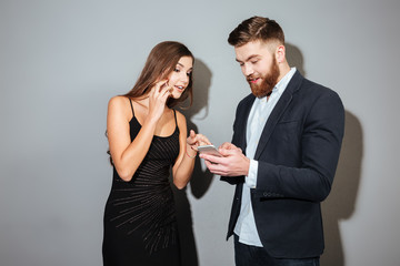 Two young businesspeople in smart wear standing with mobile phones