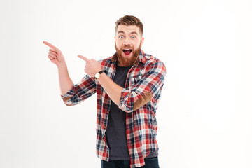 Excited cheerful bearded man pointing fingers away