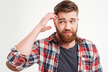 Thoughtful bearded man in checkered shirt touching his face