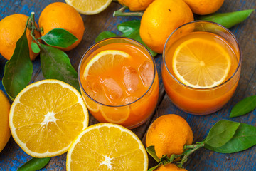 Healthy fresh citrus juice (two glasses), oranges, tangerines, lemons, ice, leaves.  Love for a healthy raw food concept
