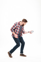 Naklejka premium Casual bearded man listening music and playing invisible guitar