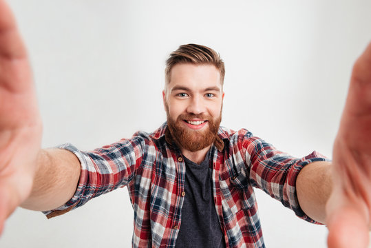 Joyful casual man taking selfie and holding camera with hands