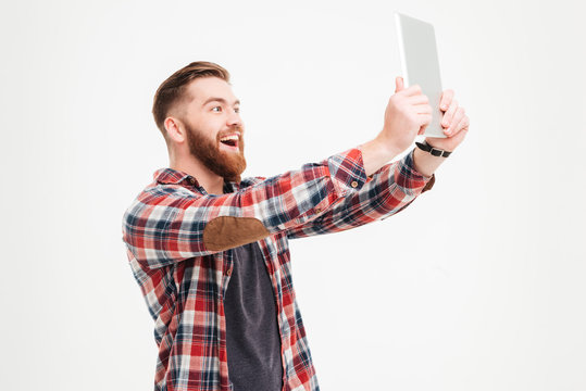 Cheerful bearded man making selfie photo on tablet computer