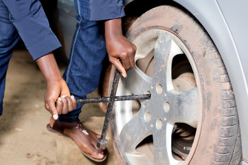 Close-up of mechanic's arms remove the tire of a car.