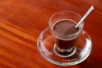 Cup of hot chocolate on the red wooden table.