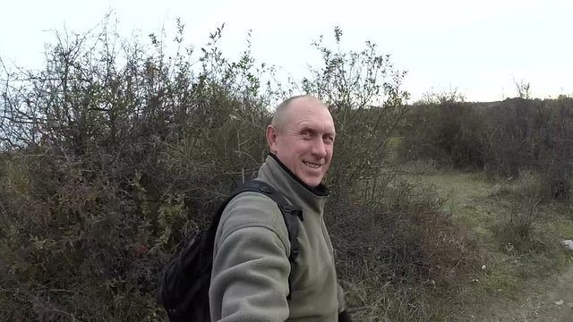 Happy man do selfie and walks outdoors on  track among bushes