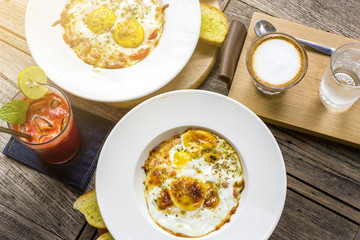 Fried eggs served on table with cappuccino coffee and mix fruits juice for breakfast
