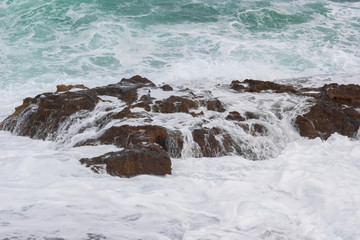 Waves crashing over the rock with white foam