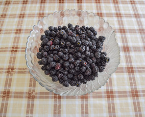 Plate with berries black blackberries. Fruits berries on the table.