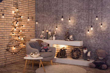 Creative wooden Christmas tree at the brick wall of Loft style room with burning bulbs garland and...