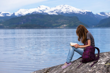 girl reading on a fjord coast