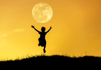 Fototapeta na wymiar silhouette happy little girl jumping to sky on sunset with full moon.