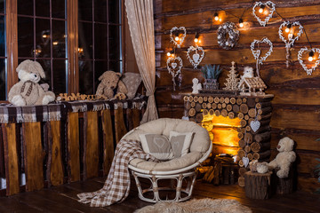Bulbs garland lights and decorativa hearts at the wooden boards wall above firewood fireplace. Winter holiday background