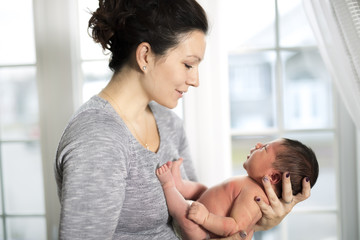 Fototapeta premium Happy mother holding adorable child baby on the living room
