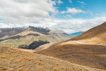 Straight empty highway leading into Aoraki-Mount Cook National Park to the highest peaks of the Southern Alps lining the horizon, South Island of New Zealand, Vintage filtered image.