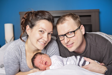 Happy family with newborn baby on the bed in the room