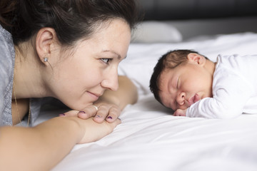 Happy mother and baby lying on bed at home