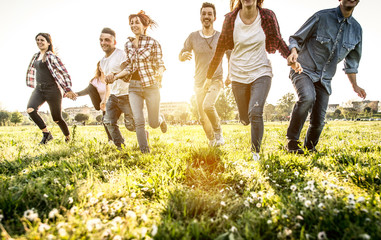 Group of friends running happily together in the grass