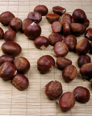 raw chestnuts on bamboo napkin over orange wooden background