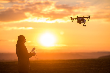 man playing with the drone. silhouette against the sunset sky - obrazy, fototapety, plakaty