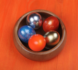 Easter composition. Colorful eggs in a wooden bowl on an orange wooden background. partially tinted photo.