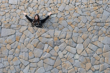 woman in layer of stone rock wall look back lift hands up in black and white dress happy face / woman and stone wall