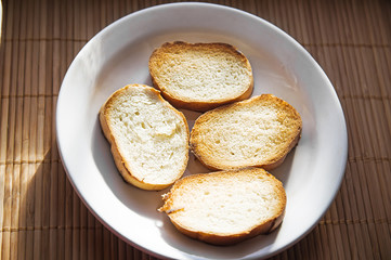 Pile of toasted bread slices on a single white plate.