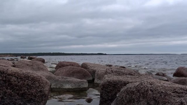 Vorgelagerte Granitfelsen an Finnischer Ostseek&uuml;ste / Finnische Insel Em&auml;salo mit Bewaldung im Hintergrund. Wellengang und graue Bew&ouml;lkung verst&auml;rken ruhigen, mystischen Eindruck.