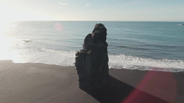 Drone footage of beautiful Reynisfjara beach with long basalt sea stack on sunny day
