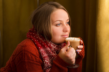 beautiful happy woman drinking cup of coffee sitting home by the window. Christmas morning. Christmas drink

