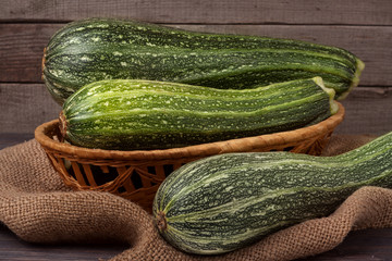 green zucchini or courgettes on sackcloth wooden background