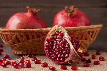 two pomegranate in a wicker basket on the old wooden board with sackcloth