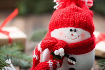 Snowman in a red cap on wooden table. Christmas decoration.