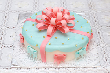 Blue mastic cake decorated with pink ribbons, closeup
