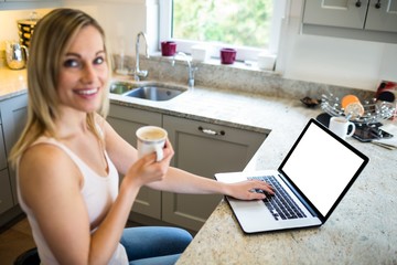 Pretty blonde woman having coffee and using laptop
