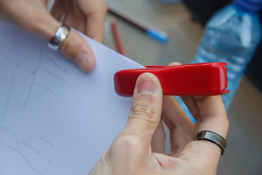 Closeup photo of a person stapling documents with a stapler on a table. 