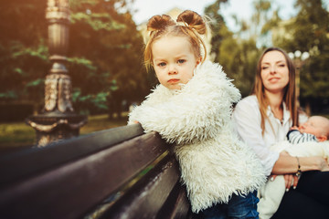 mother and two daughters rest on a bench