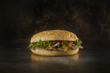 Hamburger with kebab filling. Dark metal background. Space.