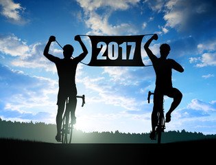 Two cyclists on bicycle at sunset. Forward to the New Year 2017