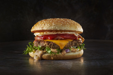 Big hamburger with lot of filling. Dark metal background. Space.