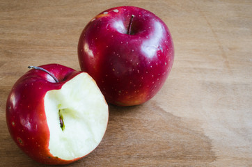 Organic whole and bitten off apples on wooden background.