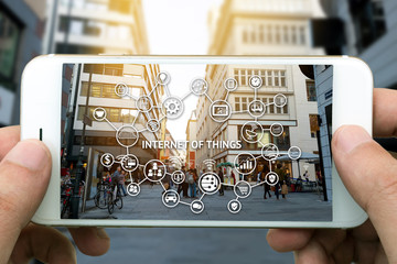 Internet of things (IoT) and digital lifestyle concept . Hand holding smart phone , wifi icons and city view background.