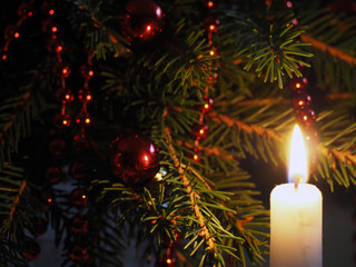 Silhouette of a burning candle on the background decorated Christmas fir tree
