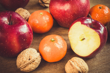 Organic apples, tangerines and walnuts on rustic wooden background.