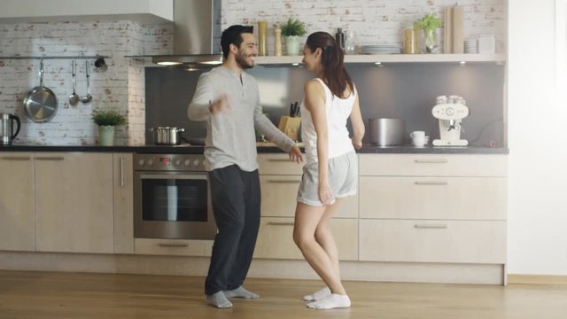  Happy Young Couple Dances in the Kitchen ending up in a Embrace. Shot on RED Cinema Camera in 4K (UHD).