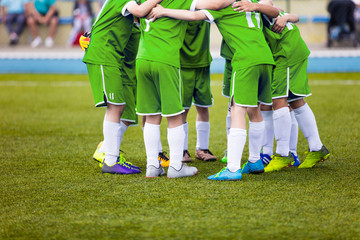 Young football soccer players in green sportswear. Young sports team on pitch. Pep talk before the final match. Soccer school tournament. Children on sports field